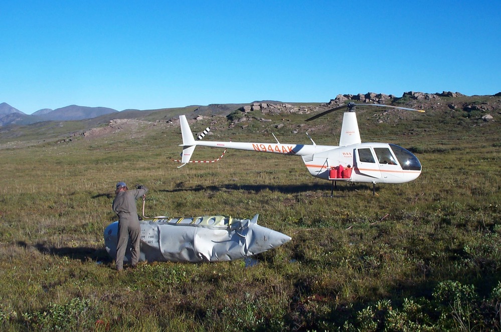 helicopter in a tundra field, next to metal container