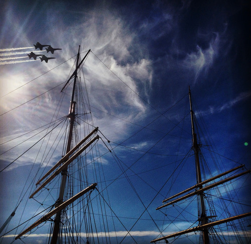 The Blue Angels fly in formation near the top of the ship Balclutha.