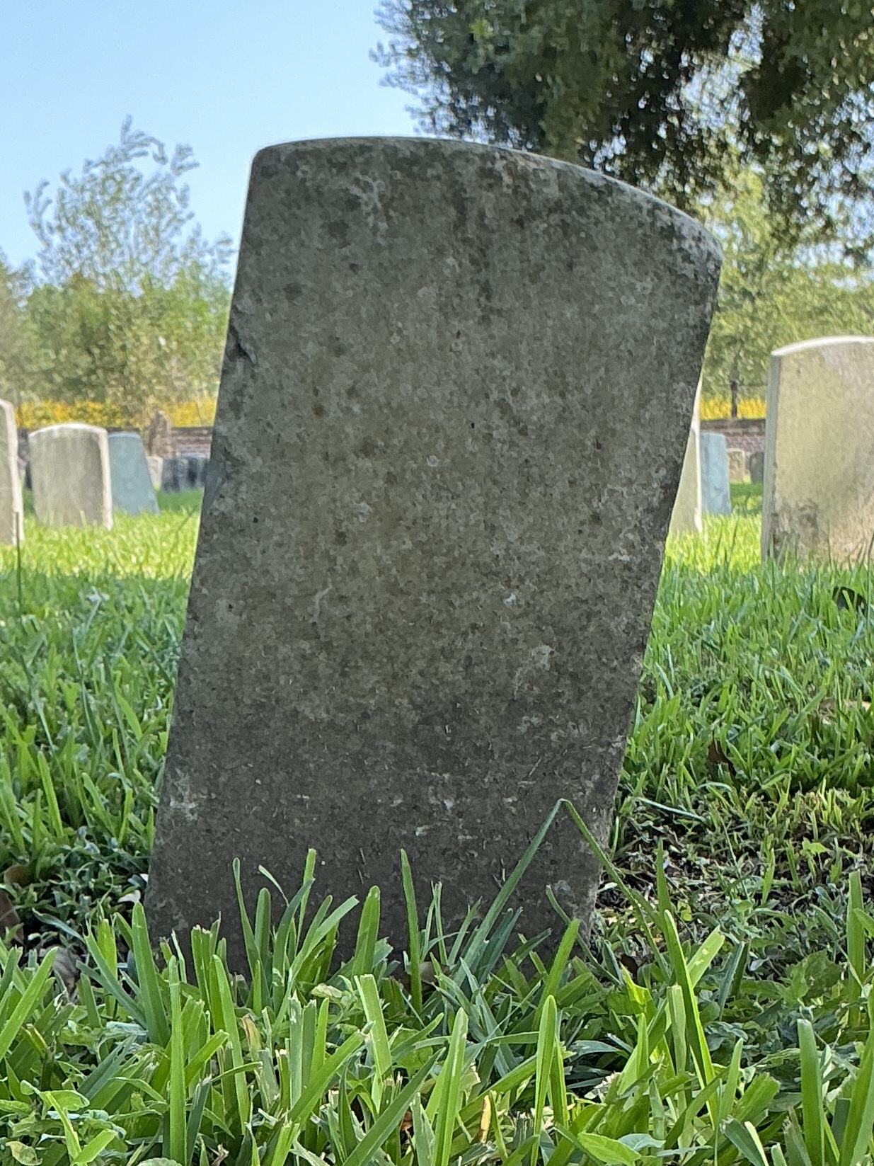 Back of historic upright marble headstone with recessed shield face.