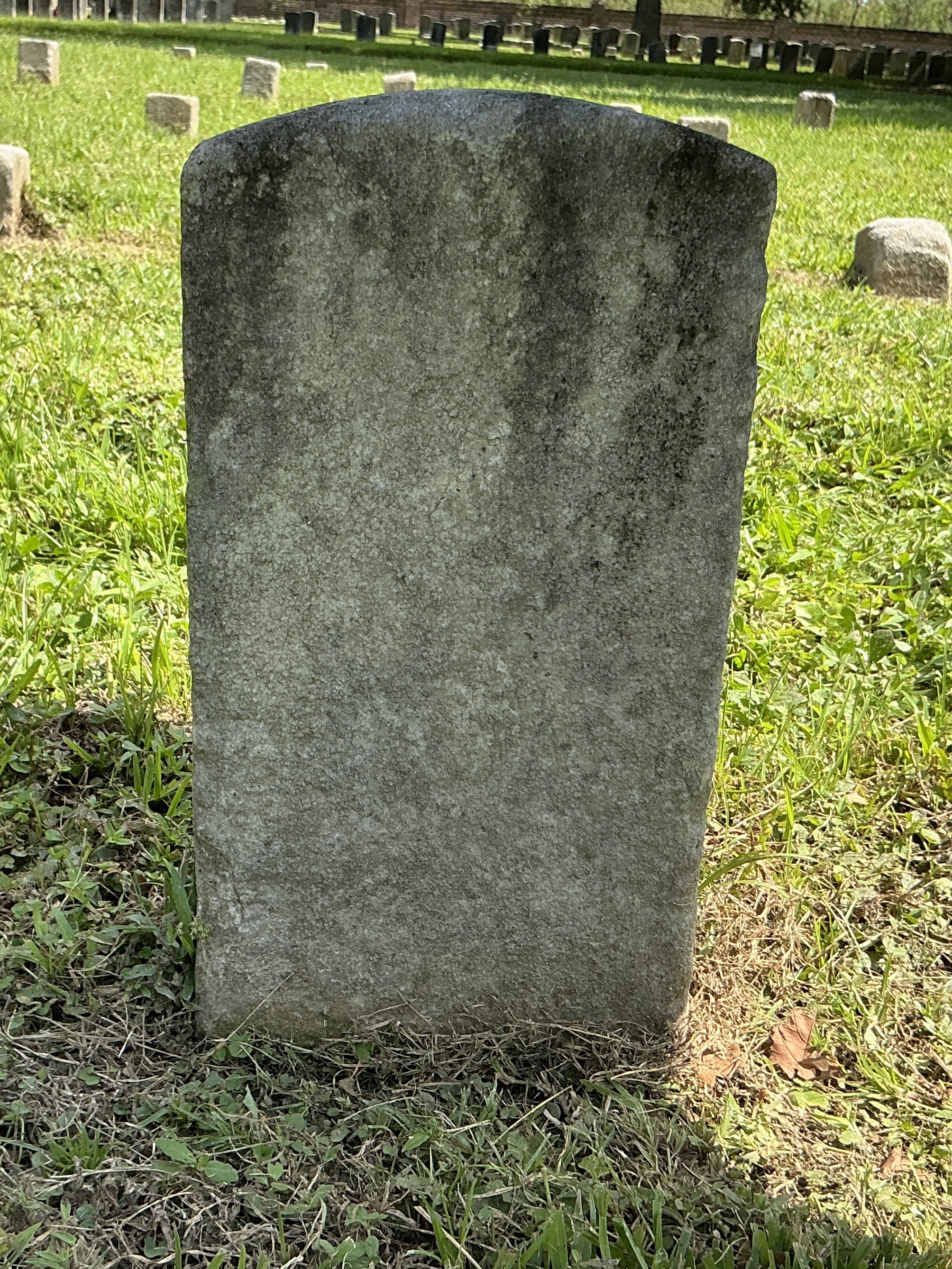 Back of historic upright marble headstone with recessed shield face.