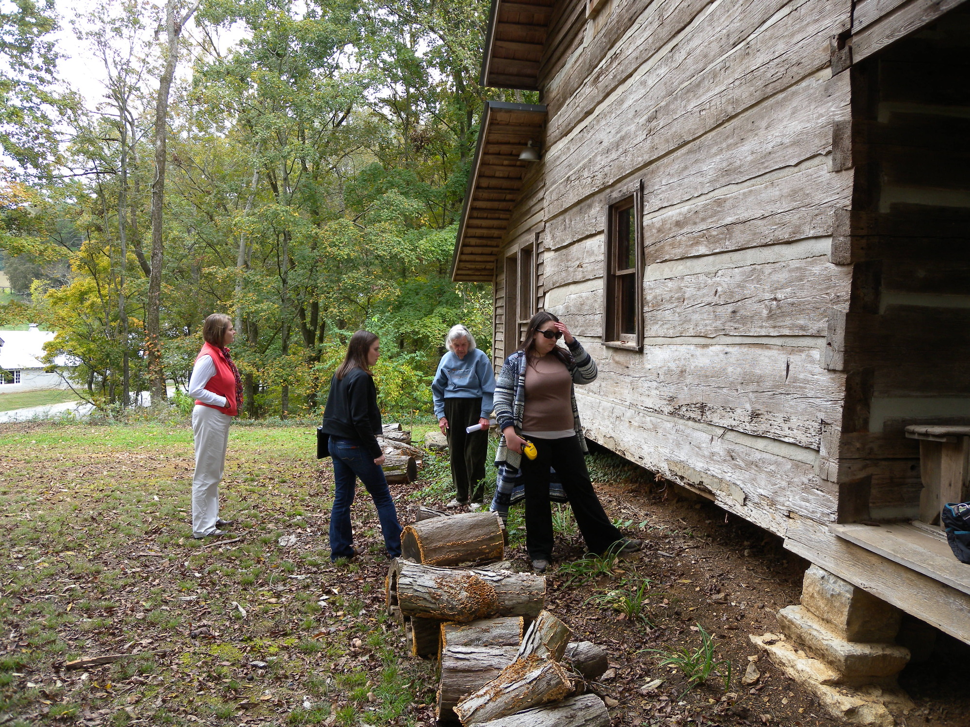 A group of people standing outside of a log cabin.