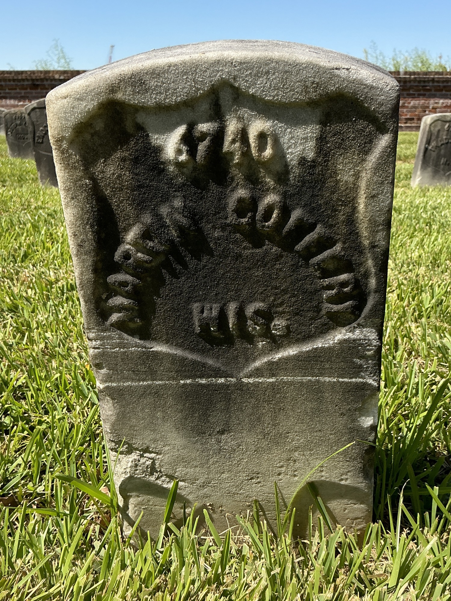 Front of historic upright marble headstone with recessed shield face.