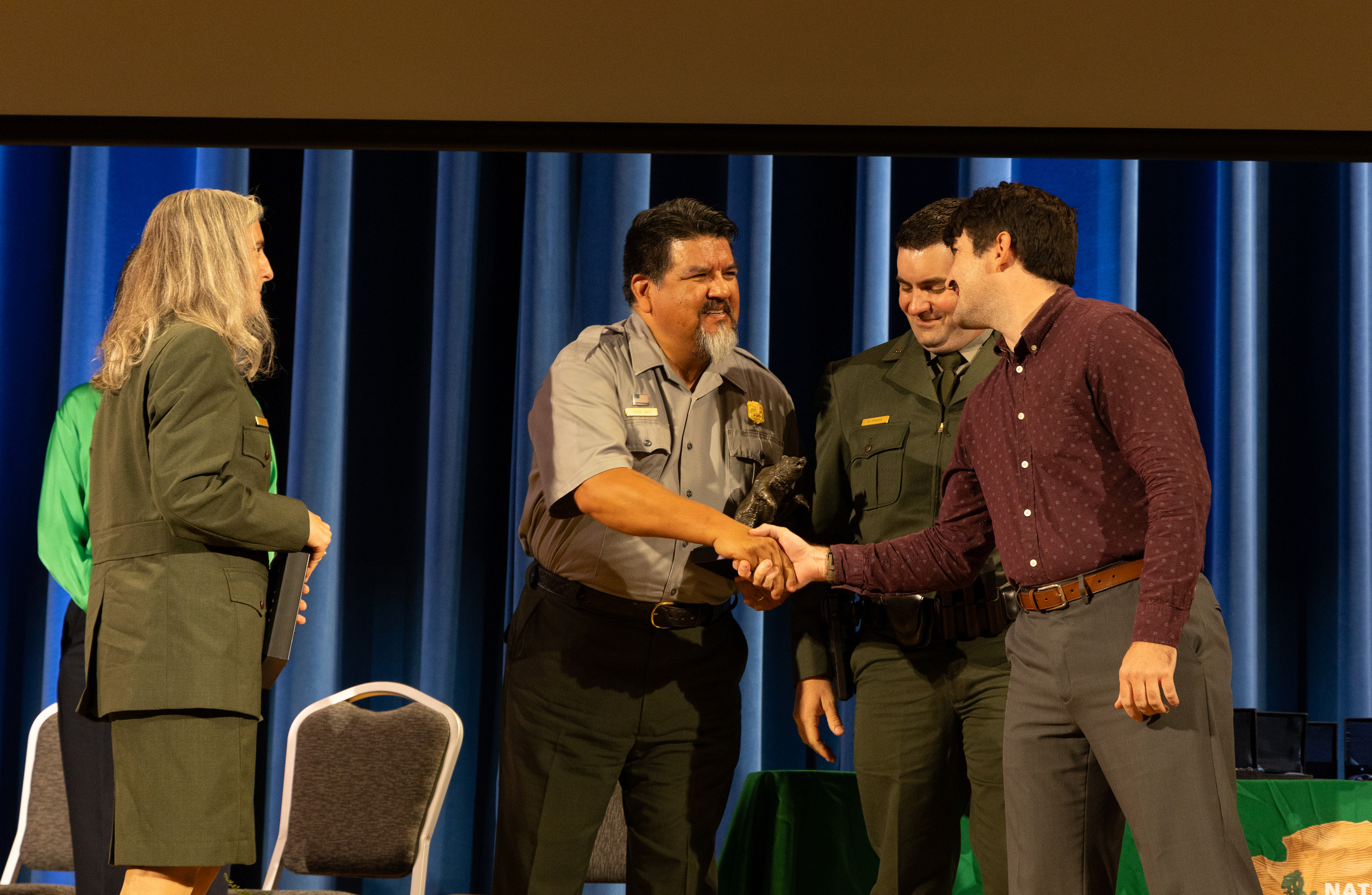 Two men shake hands on a stage during an awards ceremony.