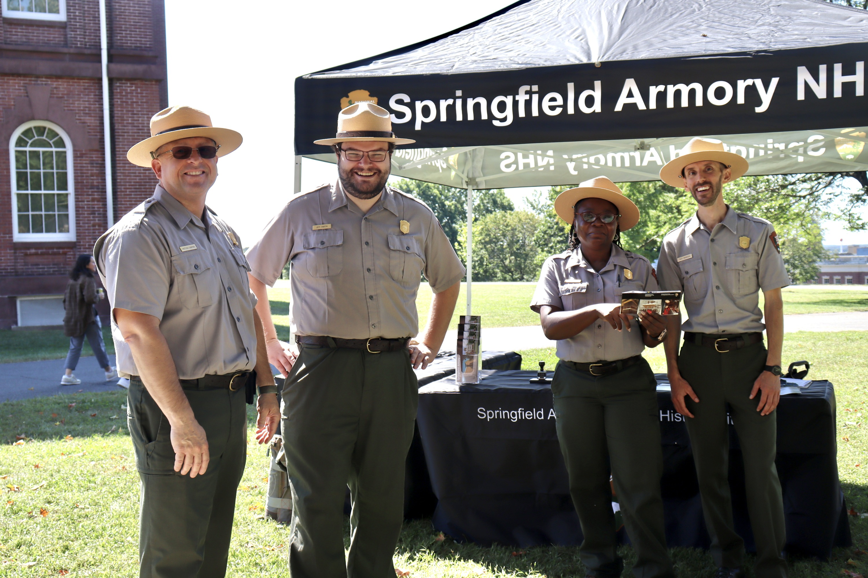 4 park rangers in uniform stand in front of a tent. 