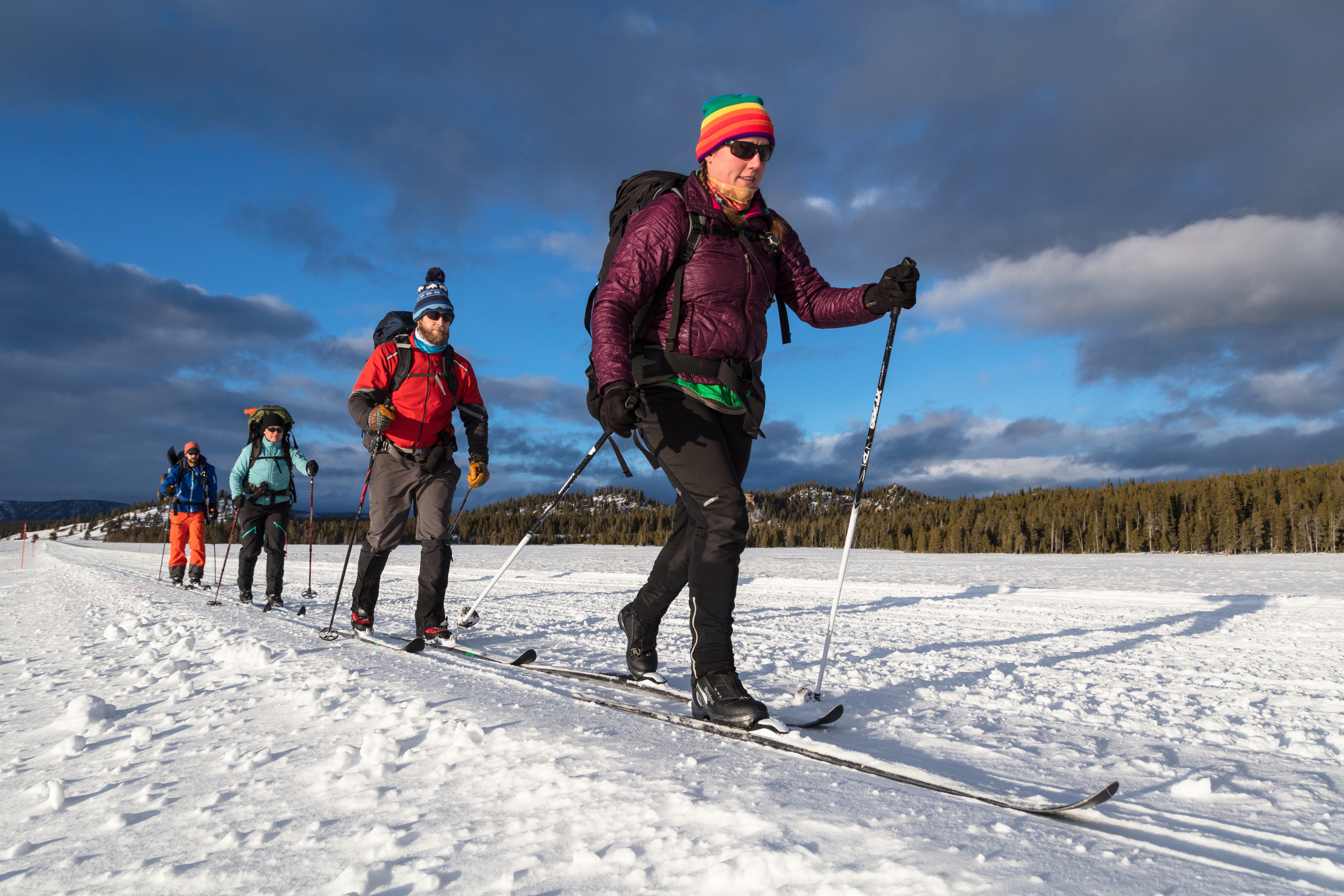 Four skiers in line skiing across open snow covered flats