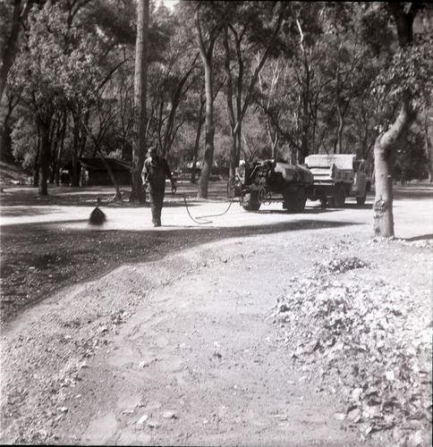 Man spraying top layer of asphalt during construction for the Grotto parking area.
