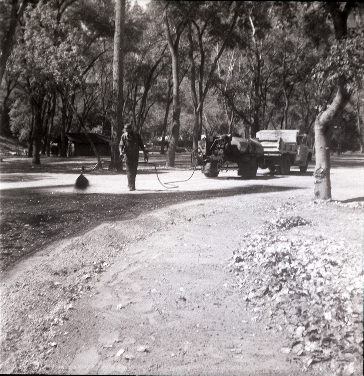 Man spraying top layer of asphalt during construction for the Grotto parking area.