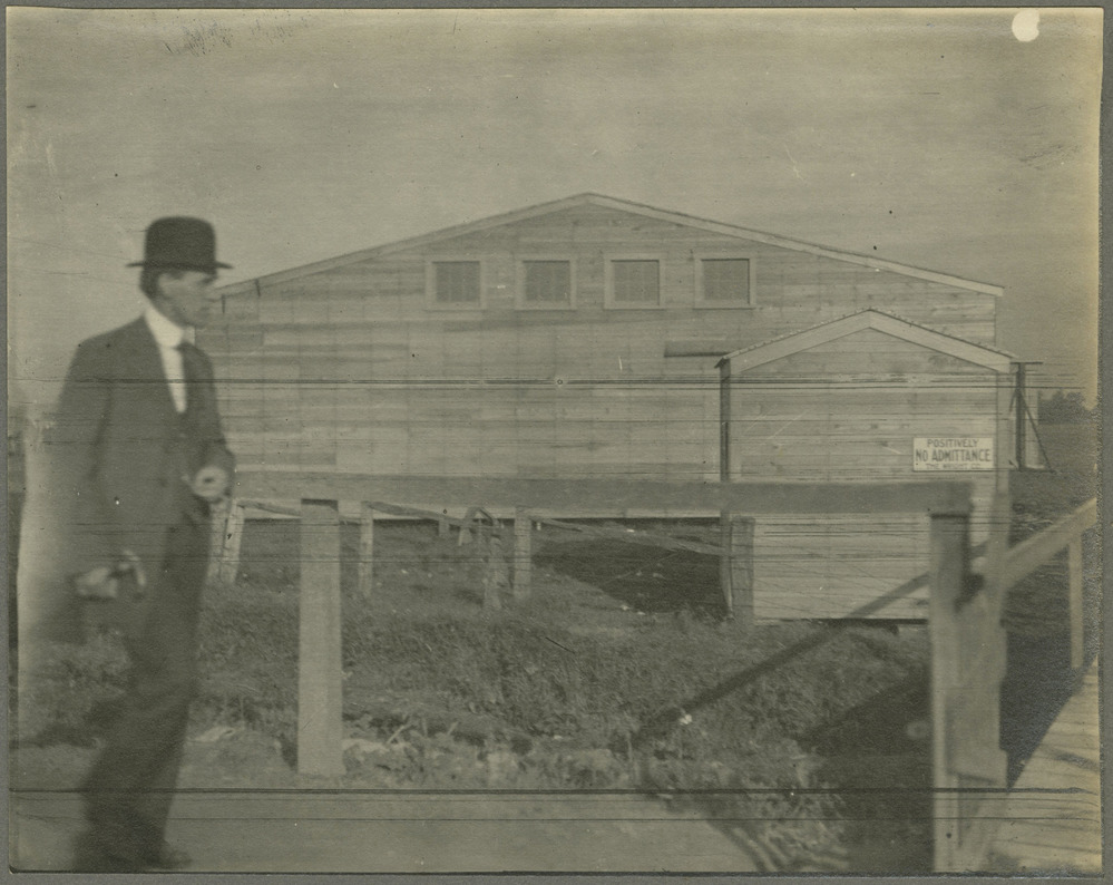 A man walks in front of wooden buidlings