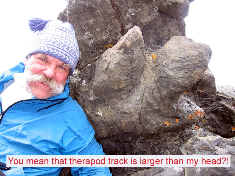 a man next to a large, fossilized footprint with three toes