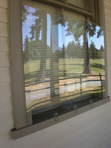 Image of clear plexiglass mounted on top of a large window. Reflection on window shows portions of park's historic Parade Ground