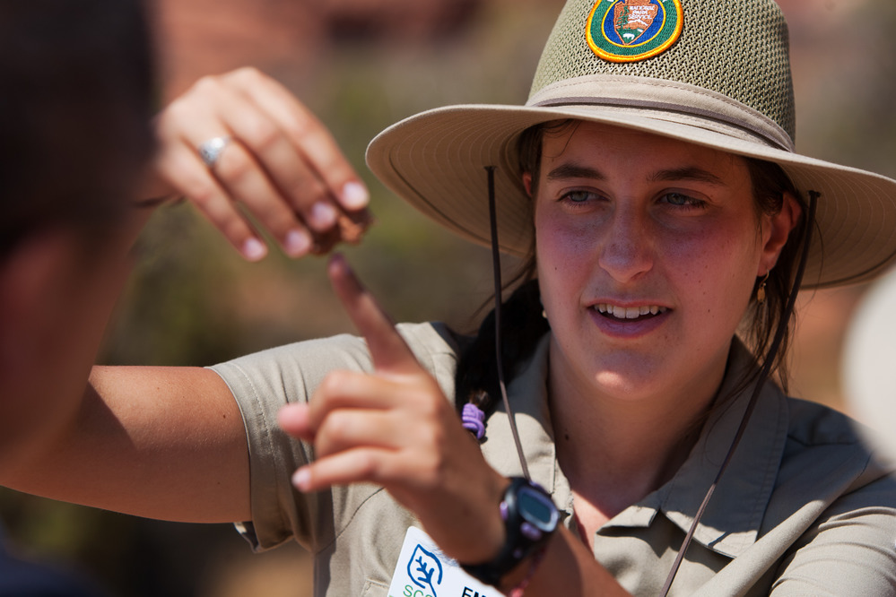 a woman in brown uniform gestures with her hands