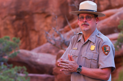 a ranger in front of a rocky landscape