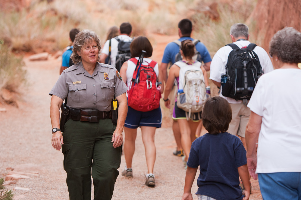 a park ranger walks on a trail with visitors