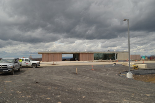 Puilding witn tan colored walls and greenish glass with grey concrete roof.