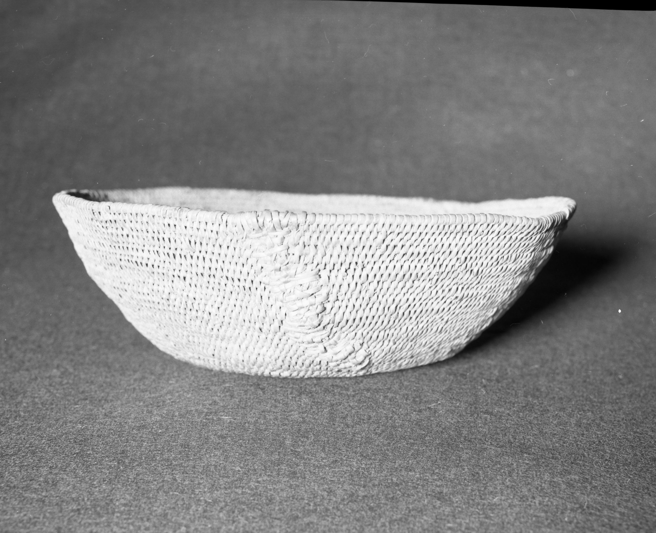 Mrs. Geraldine McConnel Collection. Object: Miwok basket. Dimensions: 9 1/2" x 3". Materials: Scrapped shoots, split bull pine branchlets. Technology: Single rod: interlocking stitch, clockspring start. Heavy repair on each side in the same material. Collection History: From a member of Mrs. McConnell's family that lived in Sonora. Thought to have been acquired from a Miwok woman in Sonora probably c. 1900. Photographed by Michael Dixon in January 1983. Catalogued by Craig Bates and Barbara Beroza. Yosemite Collections, National Park Service.