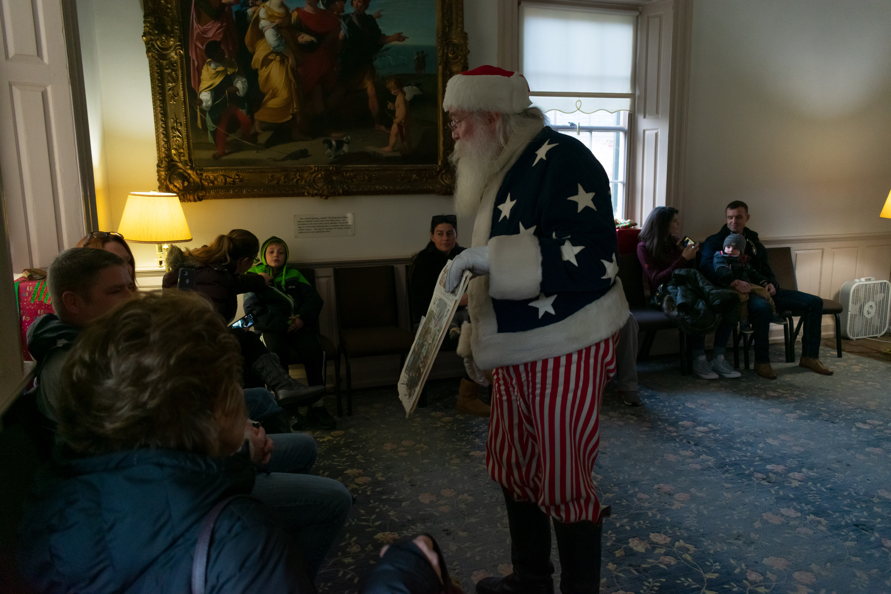 Santa Claus shows a picture to a group of visitors.