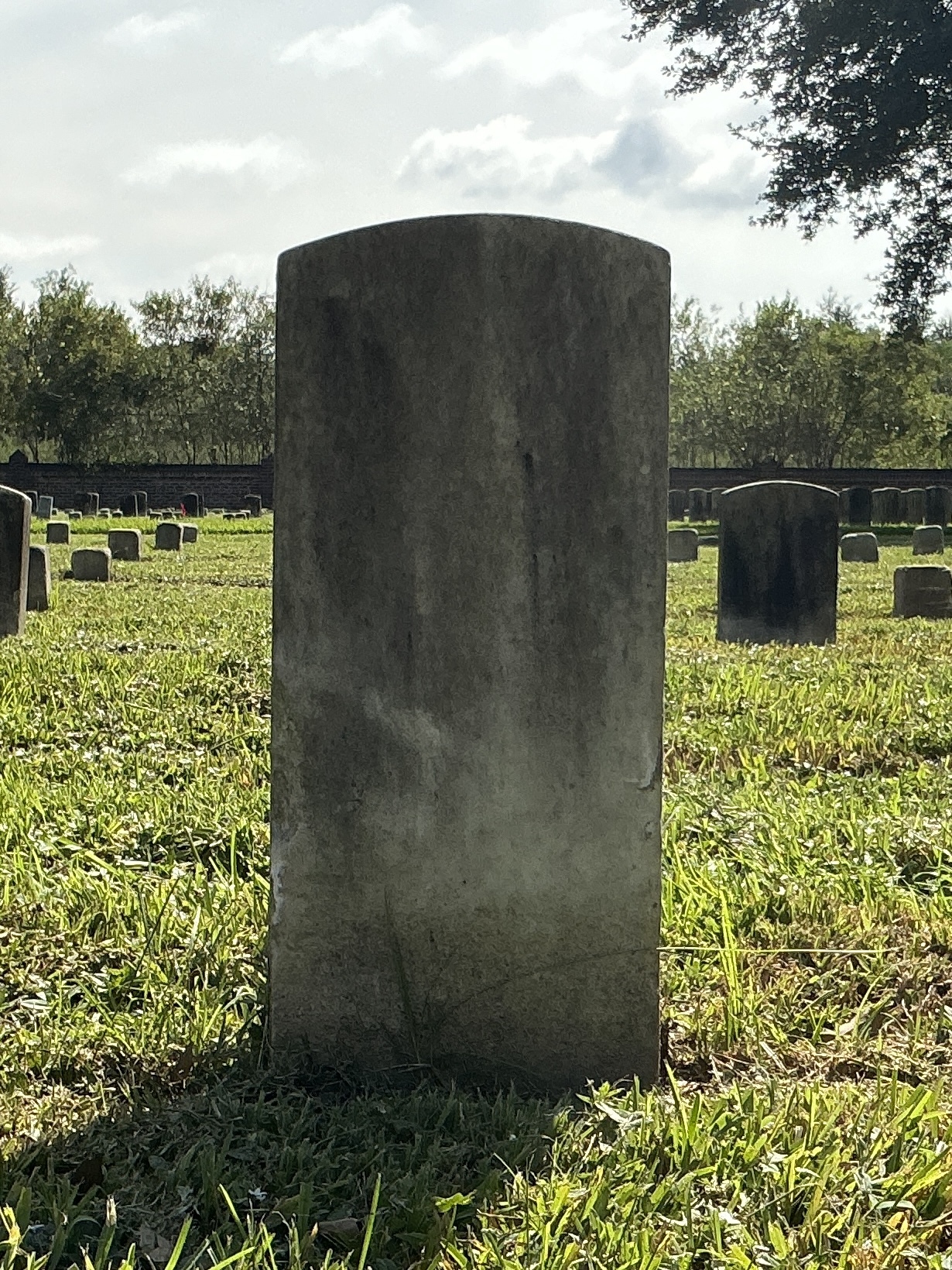 Back of historic upright marble headstone with recessed shield face.