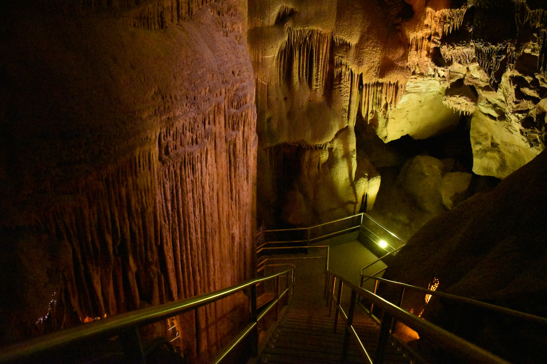 A large flowstone formation with stairs leading in front of it. 