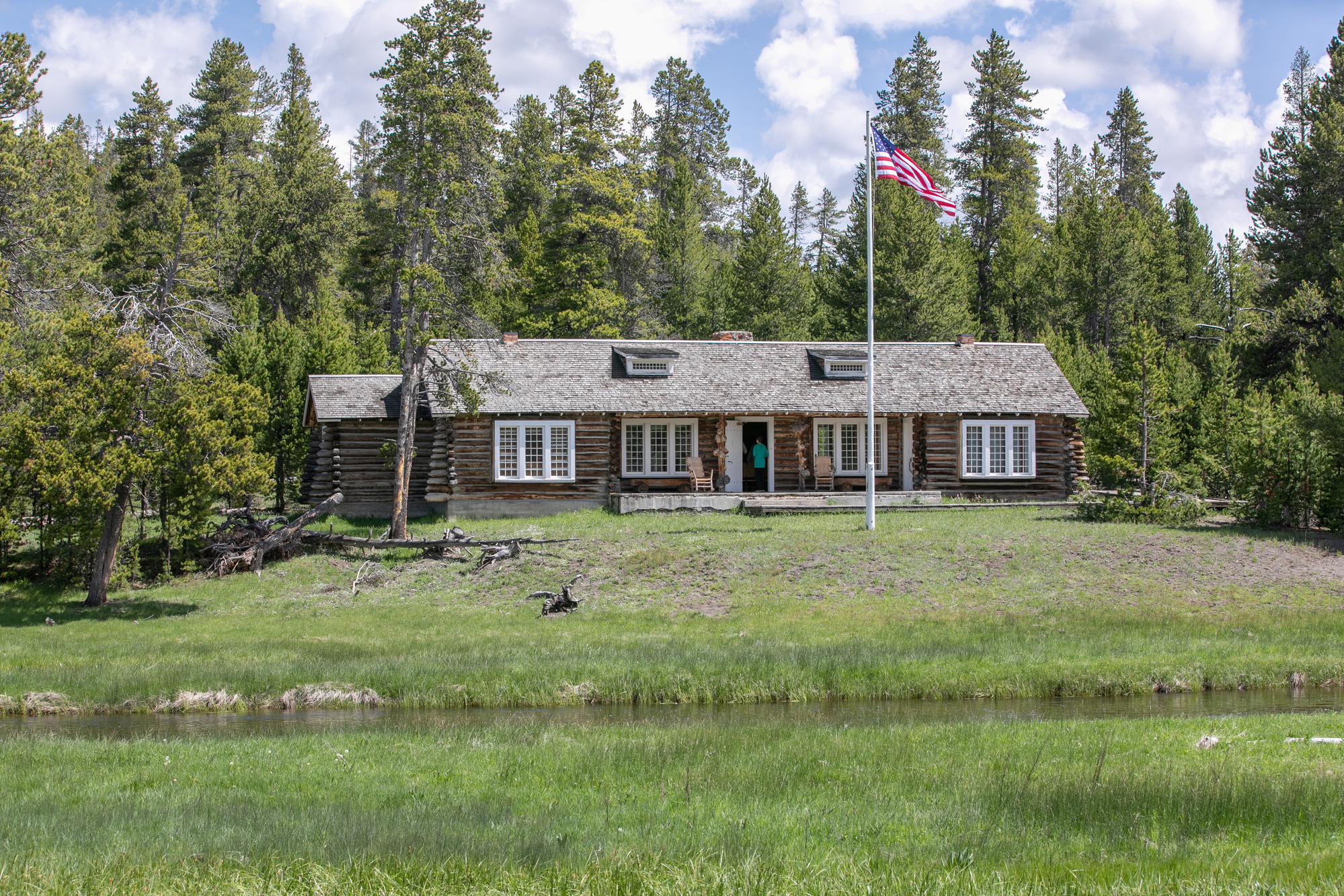 A log building with a flag out front sits by the Gibbon River.