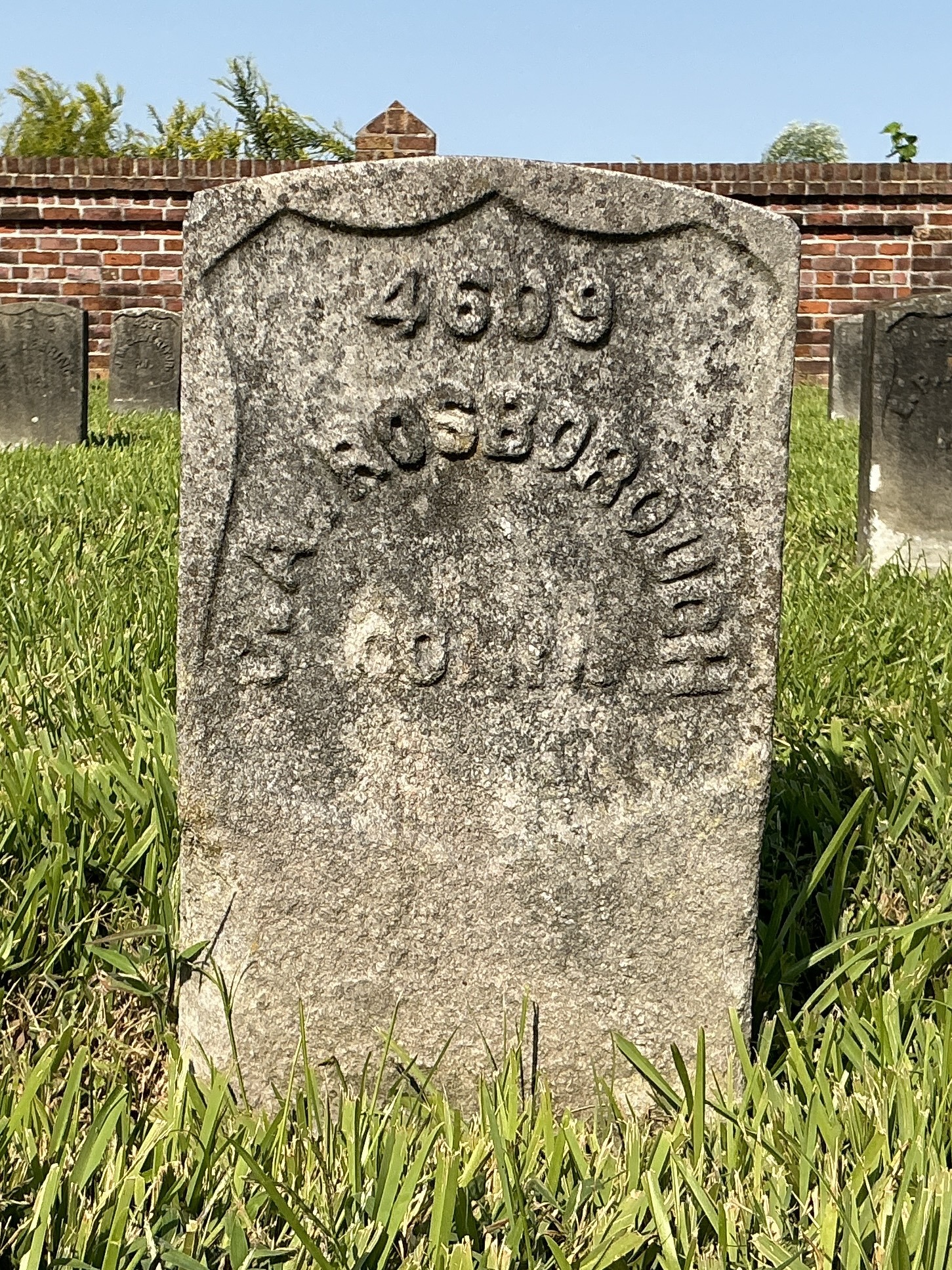 Front of historic upright marble headstone with recessed shield face.