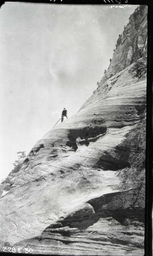 East Rim Trail construction, view looking up at worker drilling with a jackhammer on a 45 degree slope.