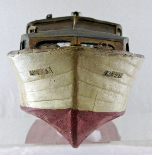 Image of a wooden model boat painted white and red.