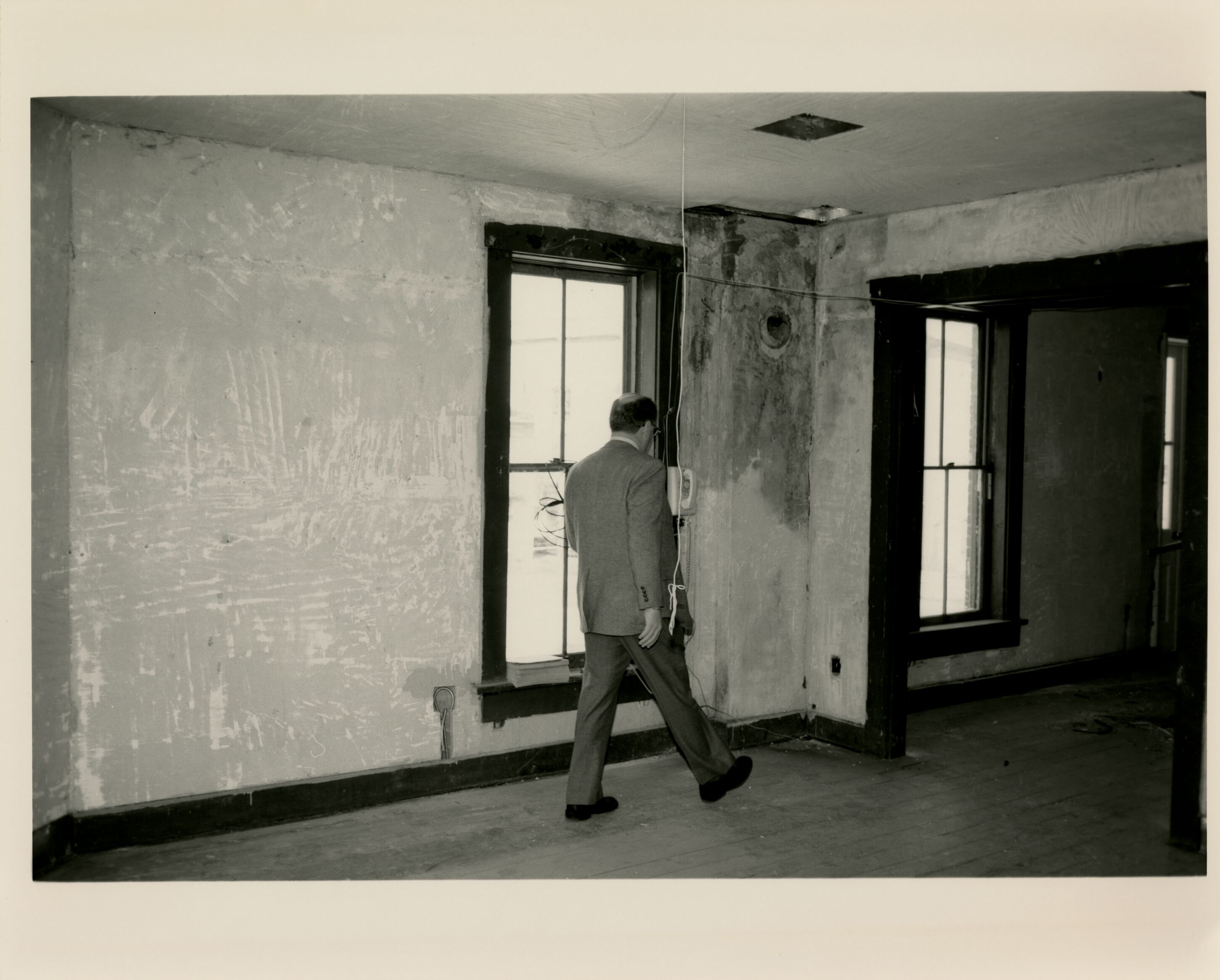 A man in a suit walking in the Wright Cycle Company during restoration
