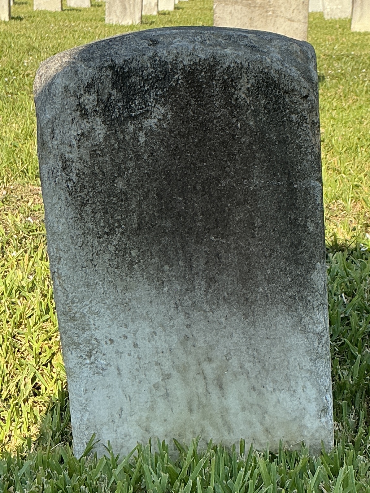 Back of historic upright marble headstone with recessed shield face.