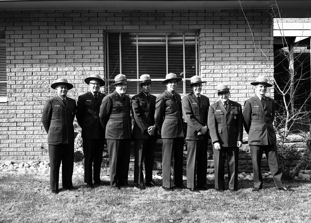 Rangers in uniform standing with Rudy Lueck (third from left) and Carl E. Jepson (second from right) outside Mission 66 Visitor Center and Museum and headquarters. Superintendent Warren F. Hamilton at far right.