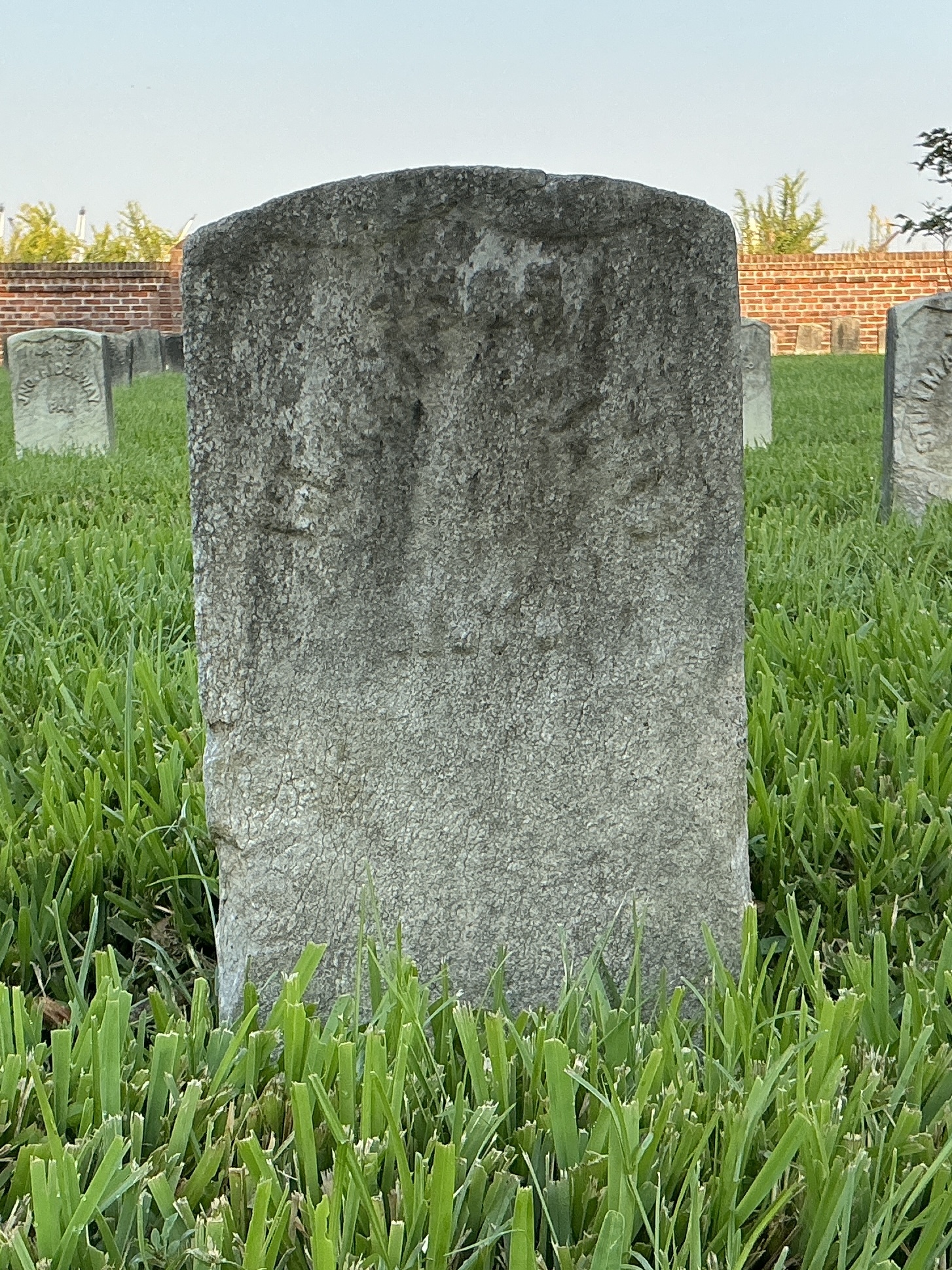 Front of historic upright marble headstone with recessed shield face.