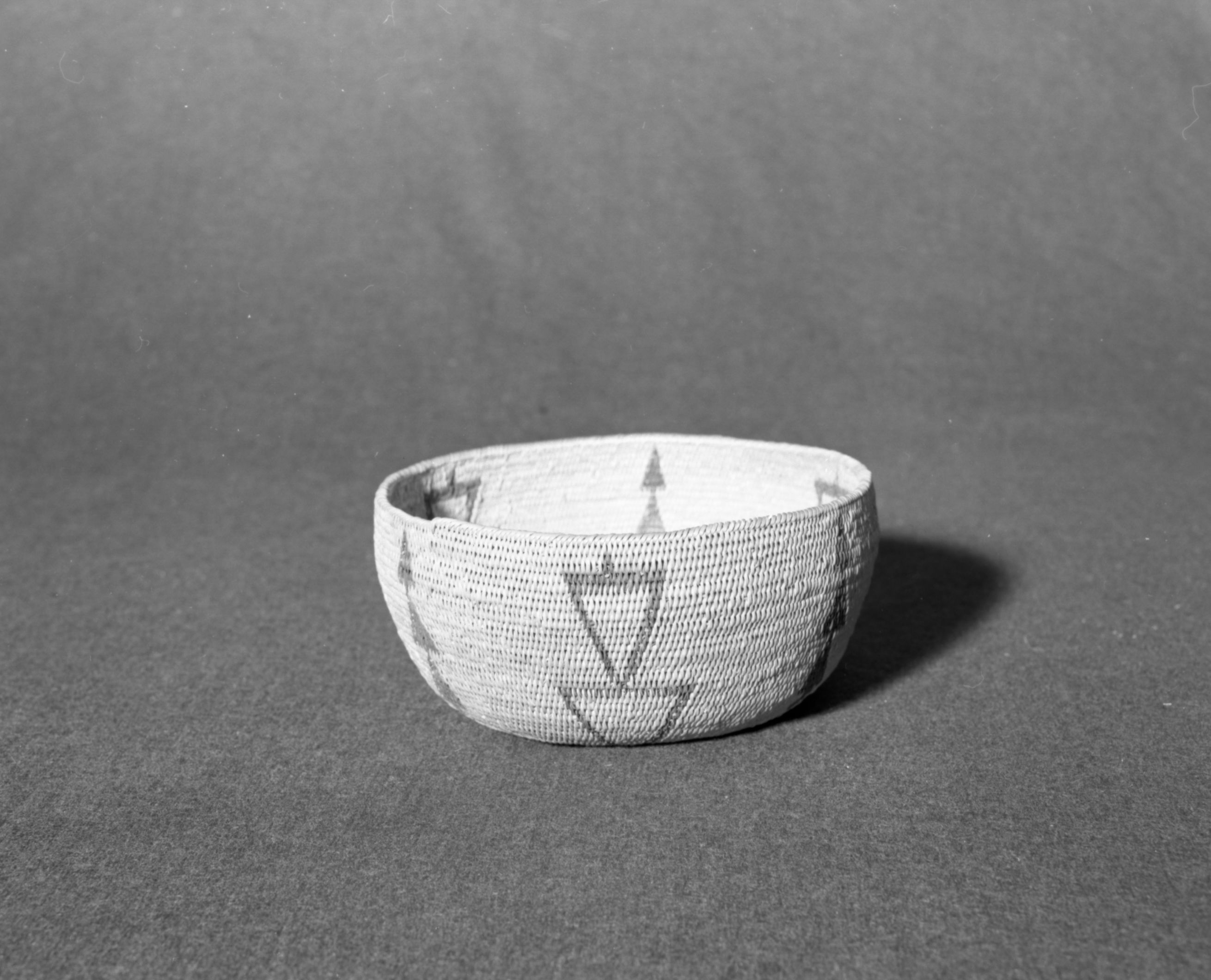 Marie Rozier Collection, Catalog No. 64. Object: Miwok basket. Dimensions: 6 1/2 x 3 1/4". Materials: split redbud, split bullpine, grass and rod foundation. Technology: fag ends trimmed on work face; moving ends trimmed on interior; clockspring start filled with shredded material. Collection History: Alice Reade collection. Photographed by Michael Dixon, December 1982. Catalogued by Craig Bates and Barbara Beroza. Yosemite Collections, National Park Service.