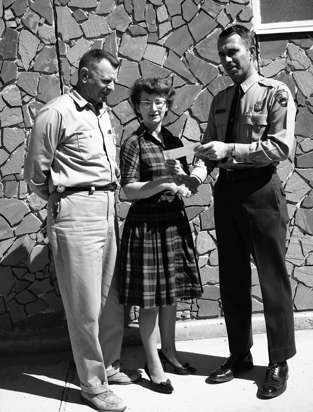 Acting Superintendent Robert Peterson presents $25 Incentive Award to Dorothy Wilmes, mail and files clerk, with her husband Ray, Buildings and Utilities foreman, at her side.