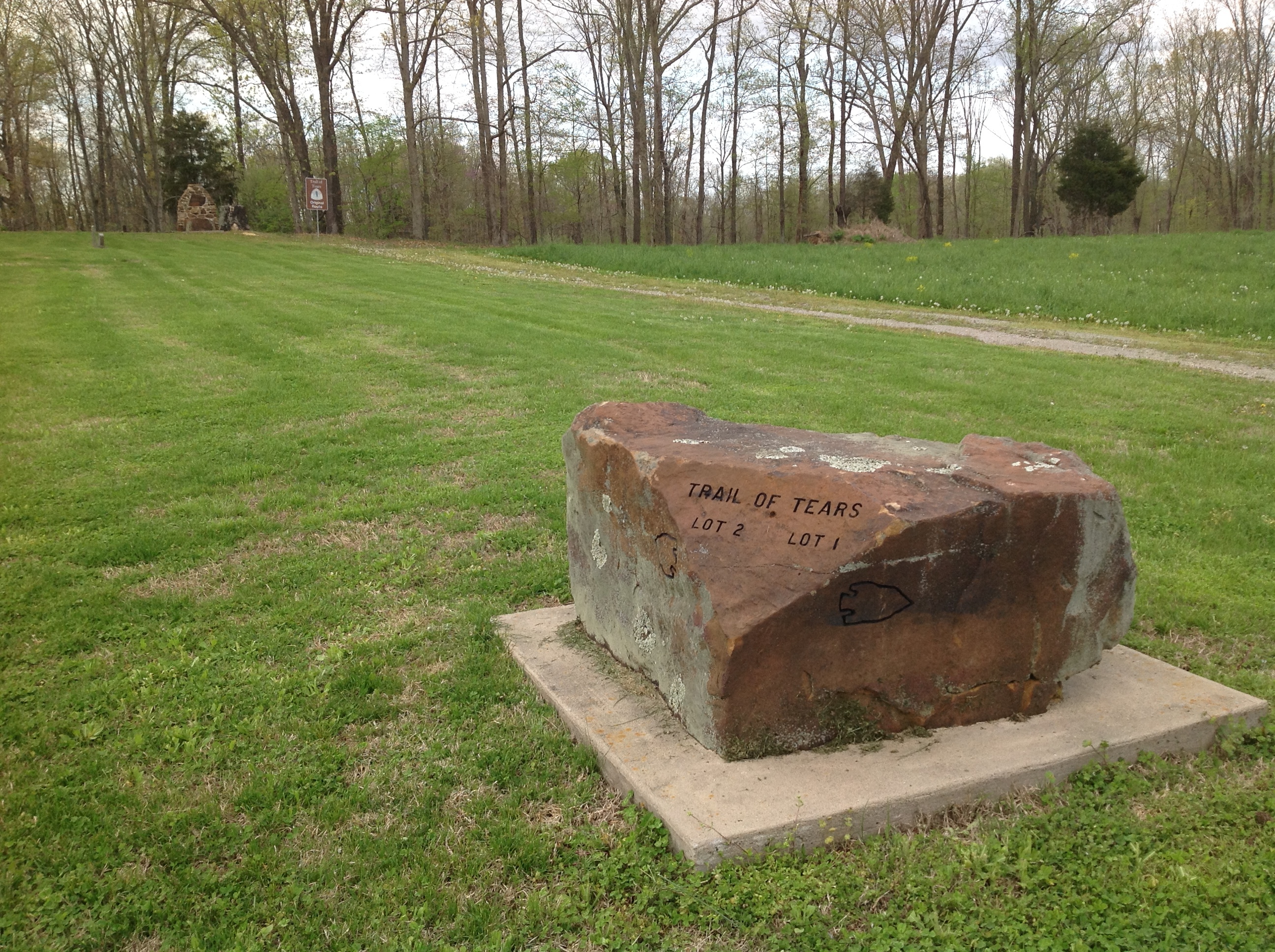 A large rock sits in the middle of a grassy field.