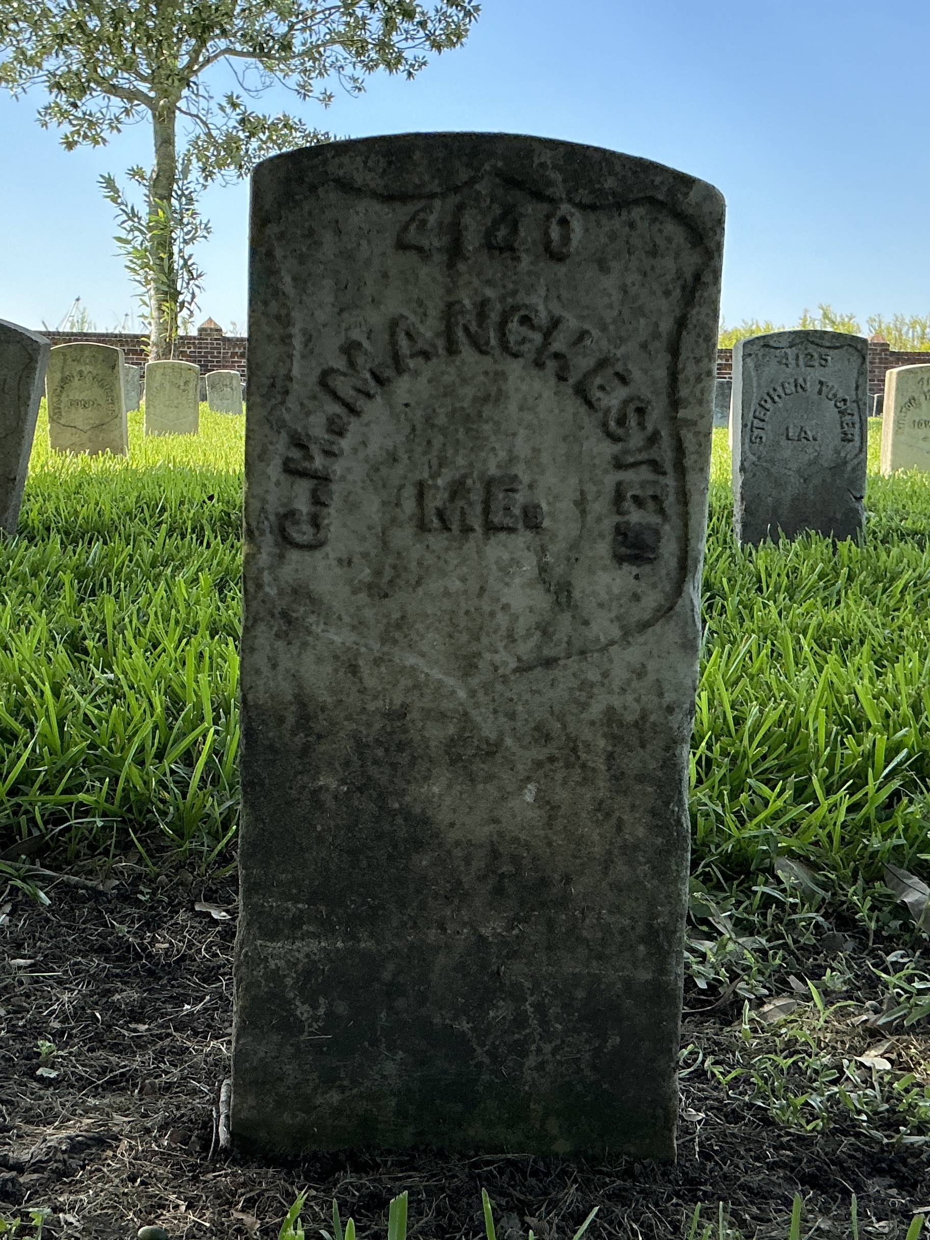 Front of historic upright marble headstone with recessed shield face.