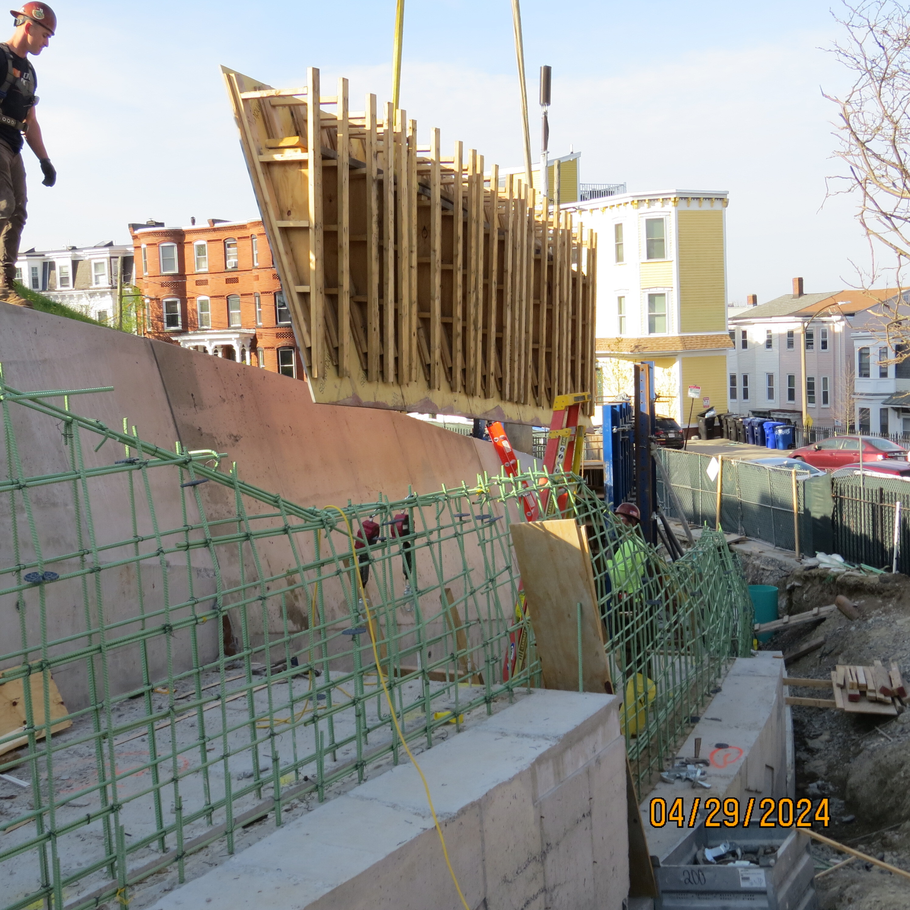 A wooden frame being removed from a concrete retaining wall. The frame hangs in the air just above the top of the retaining wall. 