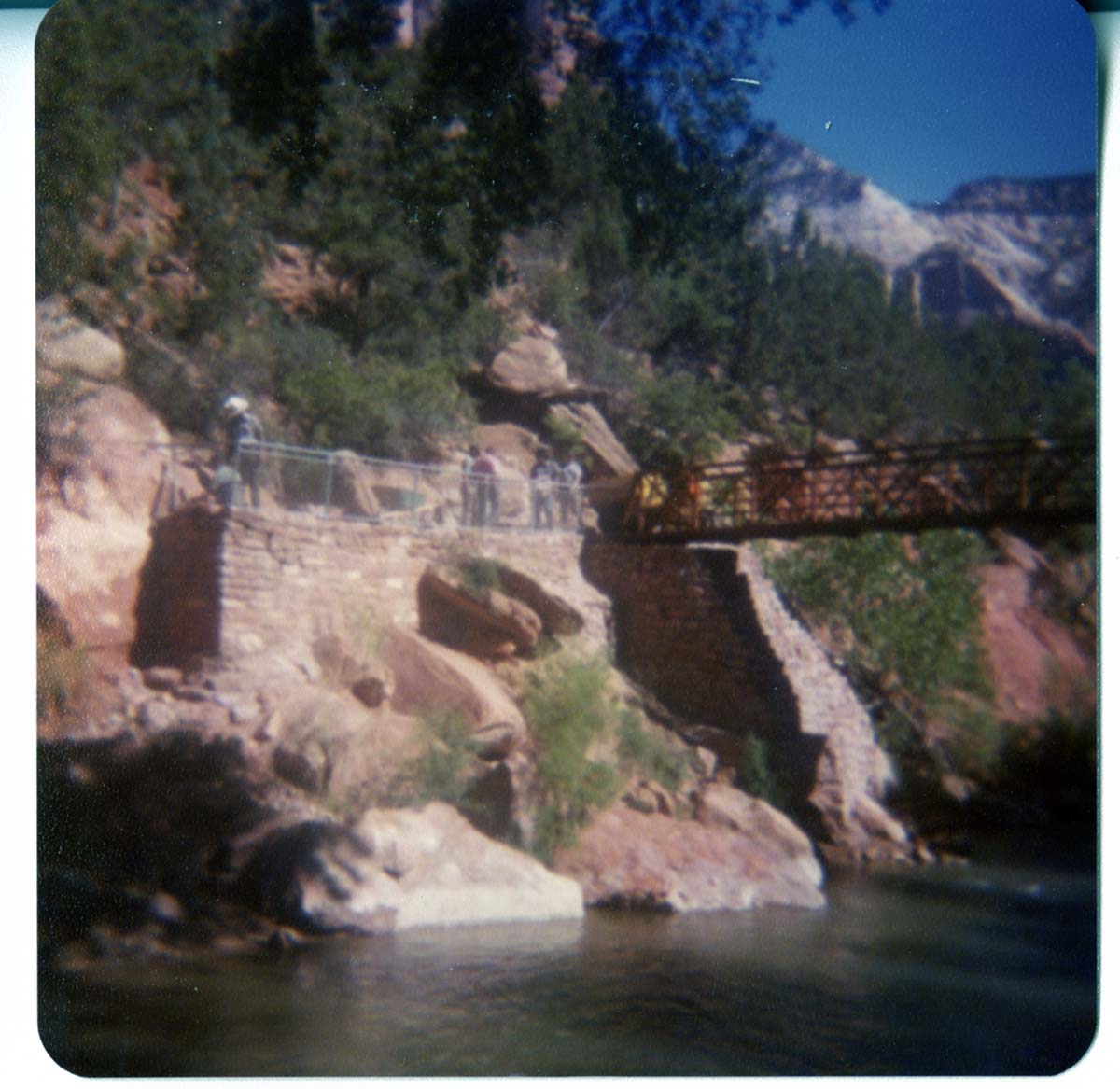 Men working on trail by the new Grotto footbridge. Overview of stone abutment for bridge and trail along Virgin River.