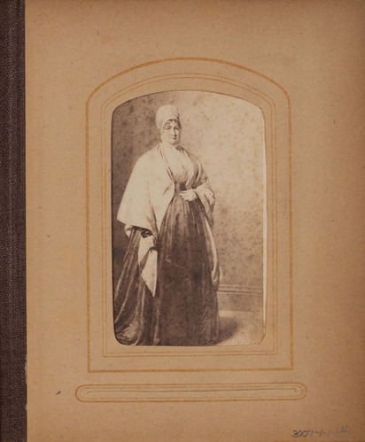Faded black and white photograph of painting featuring woman with cap and shawl.