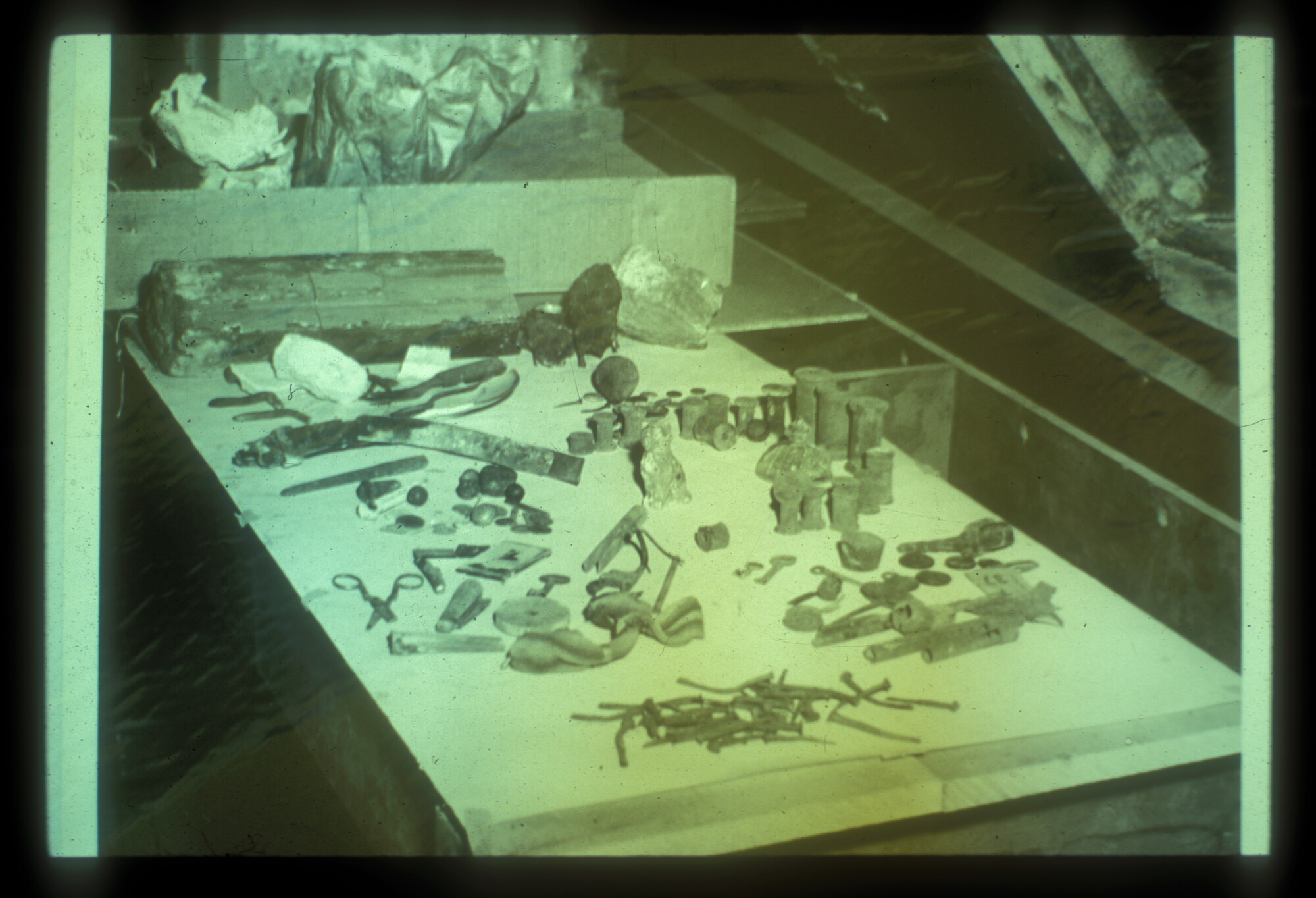 small wood and metal items grouped together on a small table. Objects were recovered during the archeological dig on site