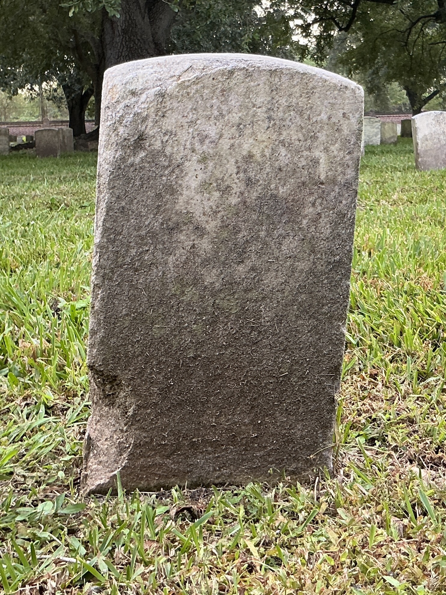 Back of historic upright marble headstone with recessed shield face.