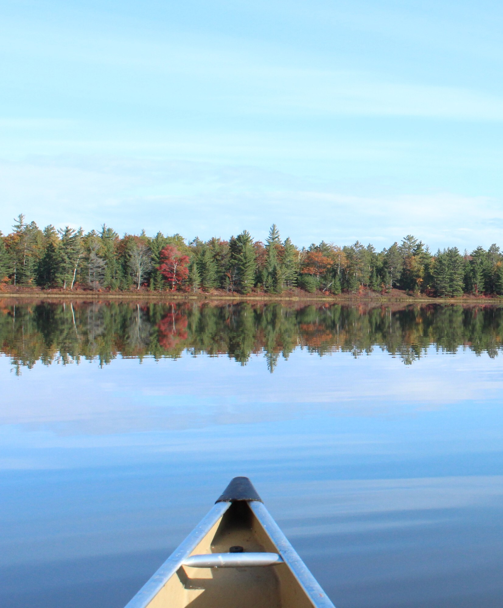 Canoeing at Beaver Basin Wilderness in calm water. Trees reflect from the shoreline