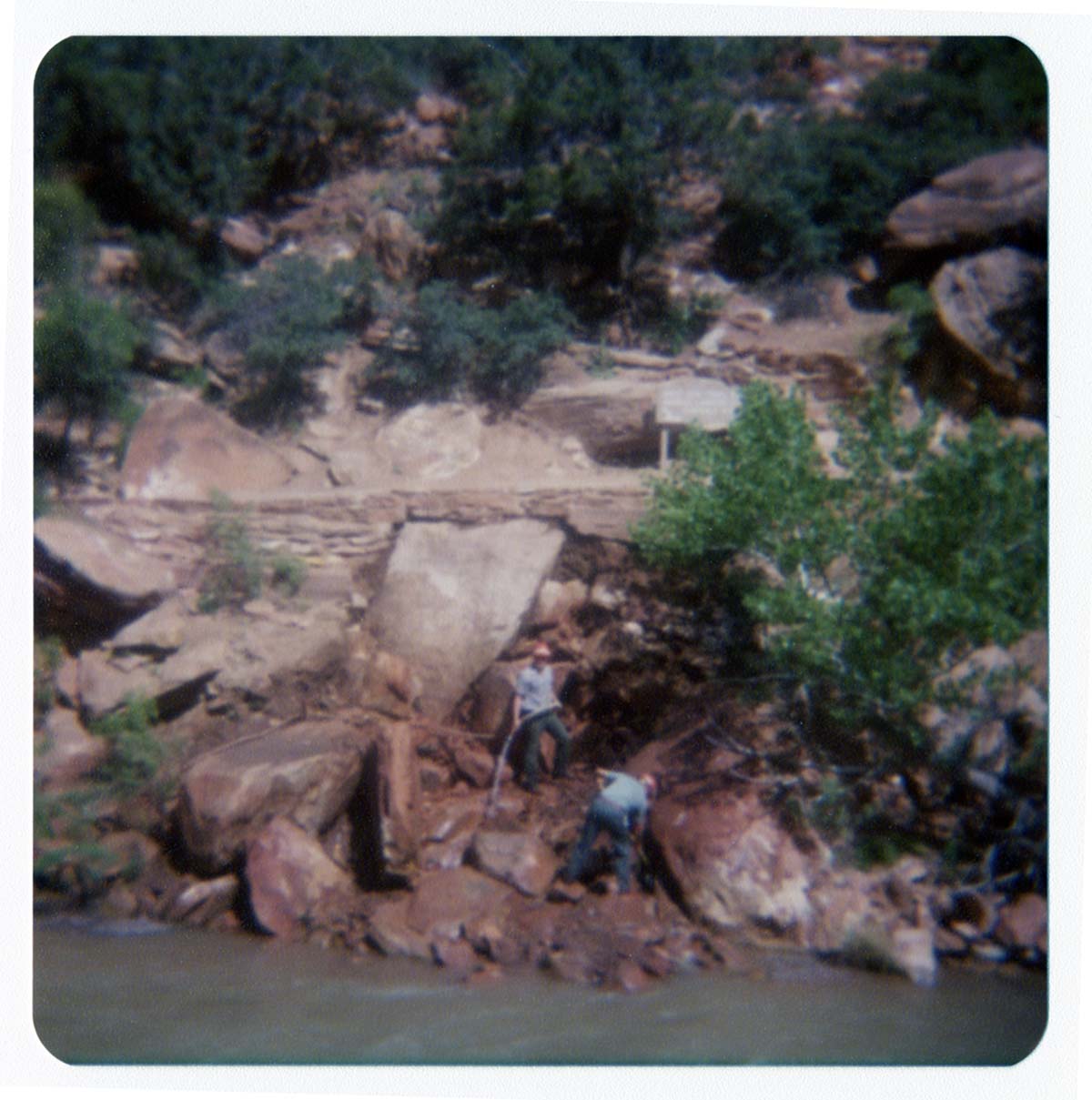 Two men using hoses to clear rubble from banks of Virgin River, in anticipation of constructing abutment for new Grotto footbridge.