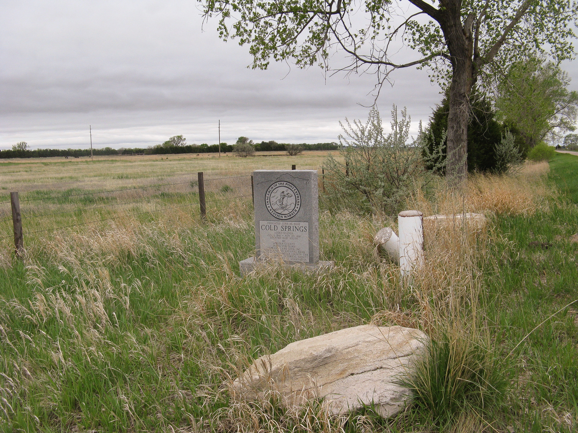 A stone monument on the edge of a grass covered field marks the location of Cold Springs Pony Express Station