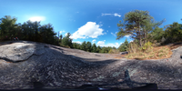 Spherical image of a rocky outcrop and trees with a view of nearby mountains