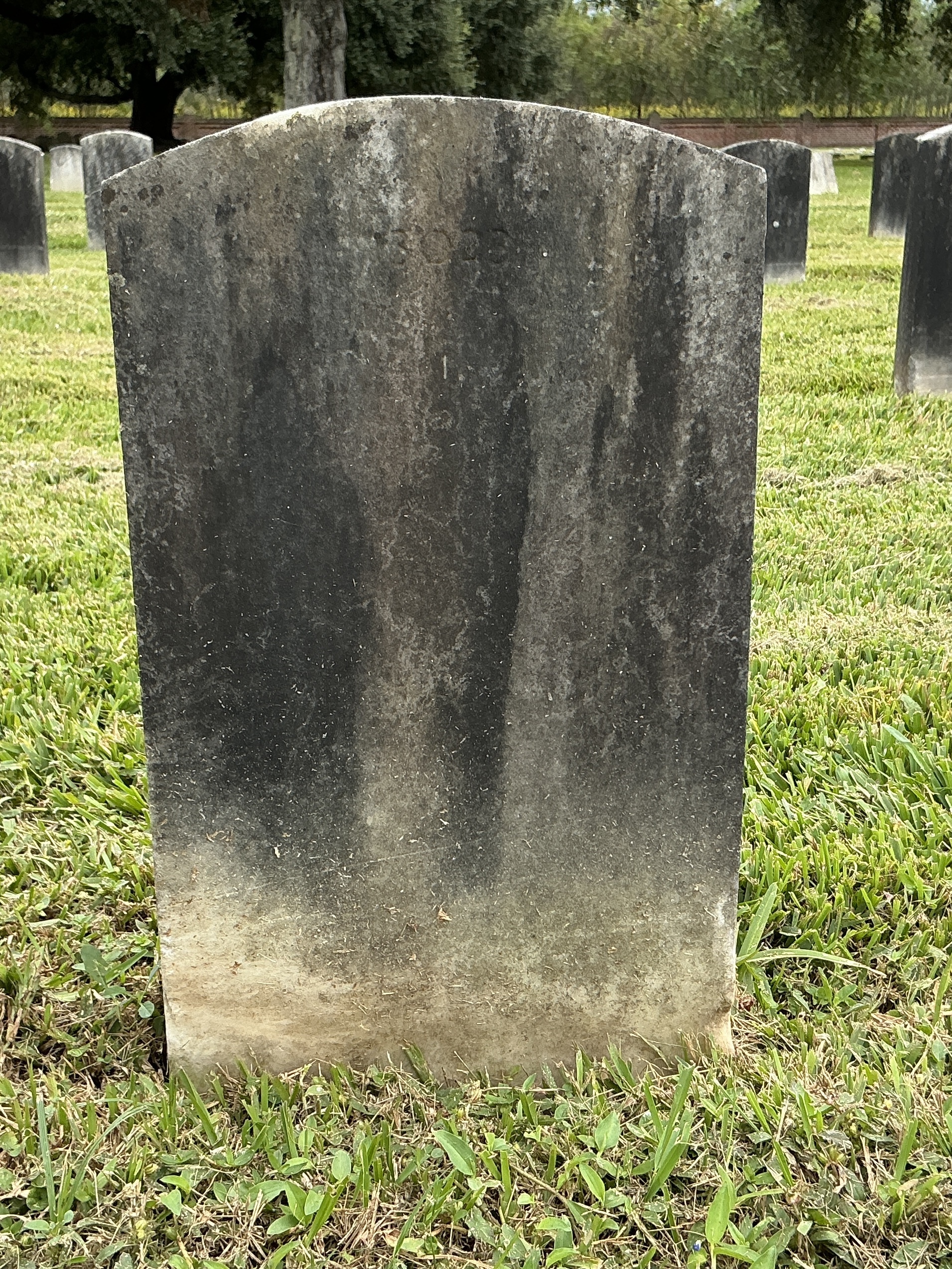 Back of upright marble headstone with flat face.