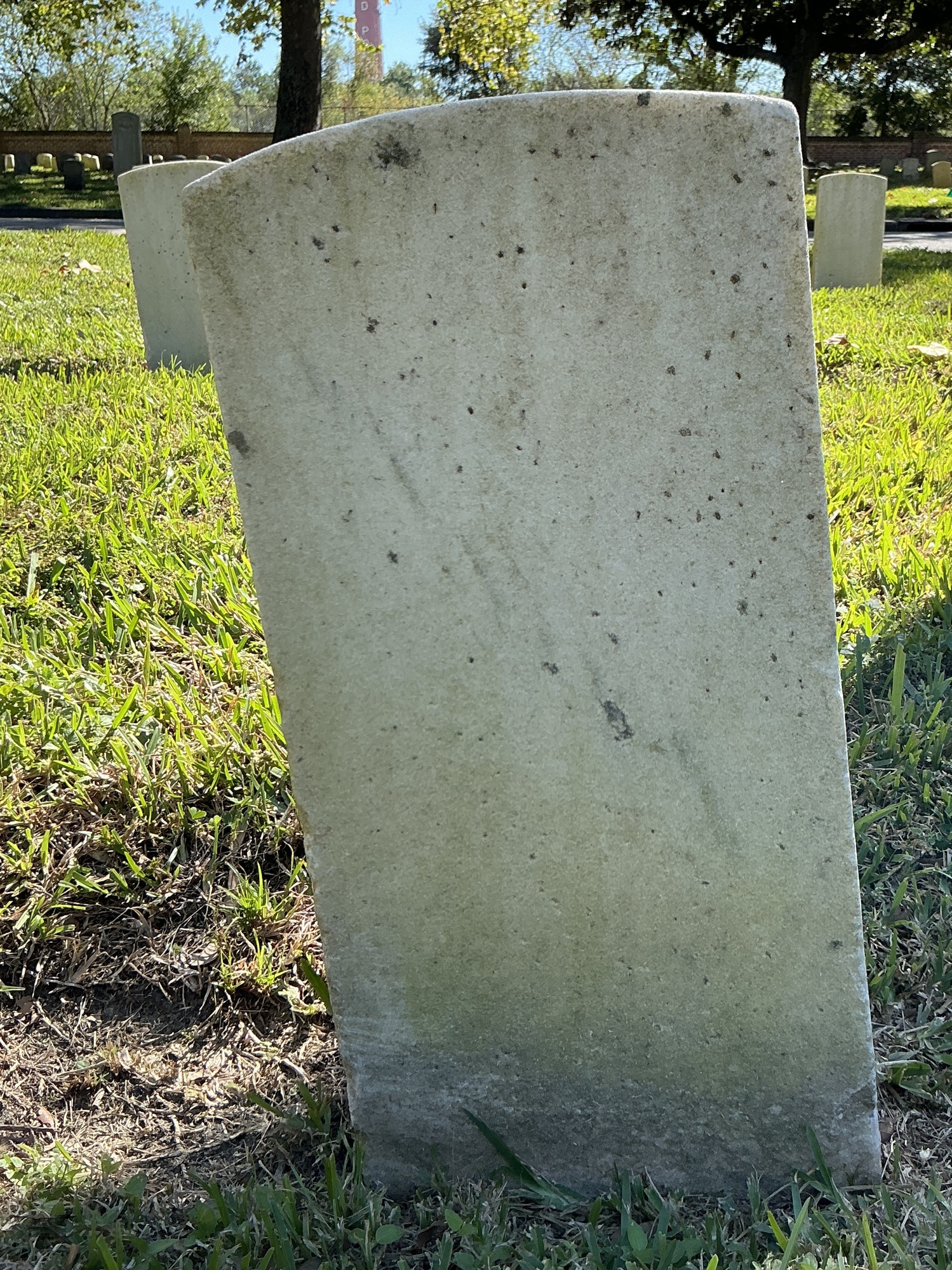 Back of historic upright marble headstone with recessed shield face.