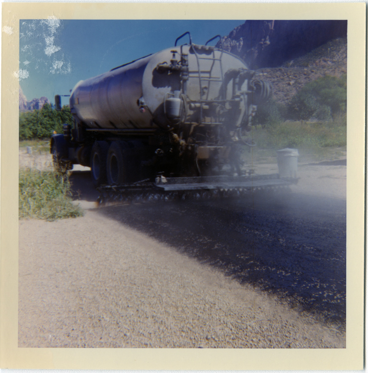 Chipsealer truck spraying top layer of chipsealer during road work.
