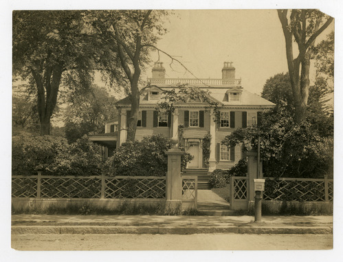 Facade of Georgian mansion with fence, black and white photo.