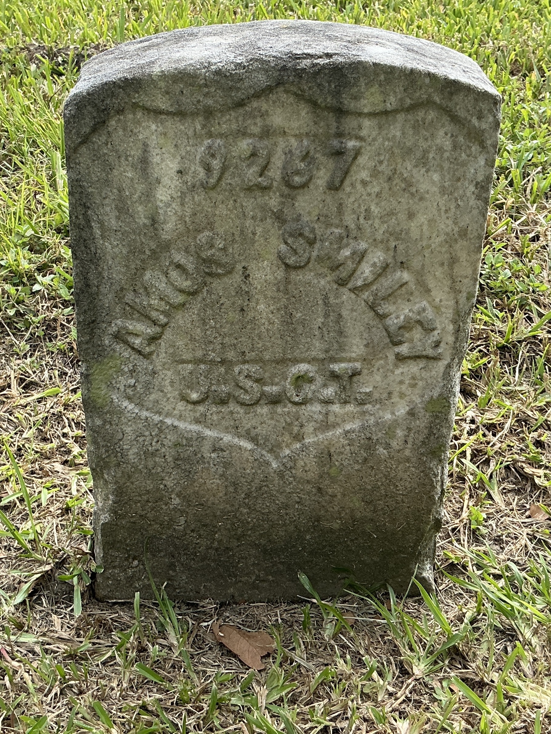 Front of historic upright marble headstone with recessed shield with recessed lettering face.