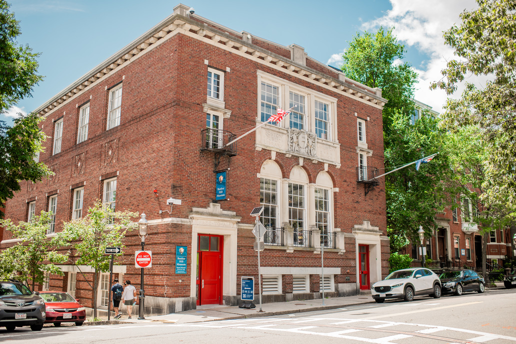 Red brick building with two flag poles sticking out 