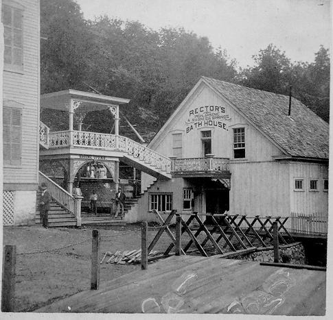 Double black & white image for viewing through stereoscope
View of Rector's Bathhouse & Arsenic Spring with wooden bridge over Hot Springs Creek in
foreground; a few people barely visible in doorways. Pale yellow border & back;
"Rector Bath House" printed in ink on back
Soiled; images yellowed & faded (right side more so)
This cat. no. originally assigned to a duplicate of print HOSP 1894.